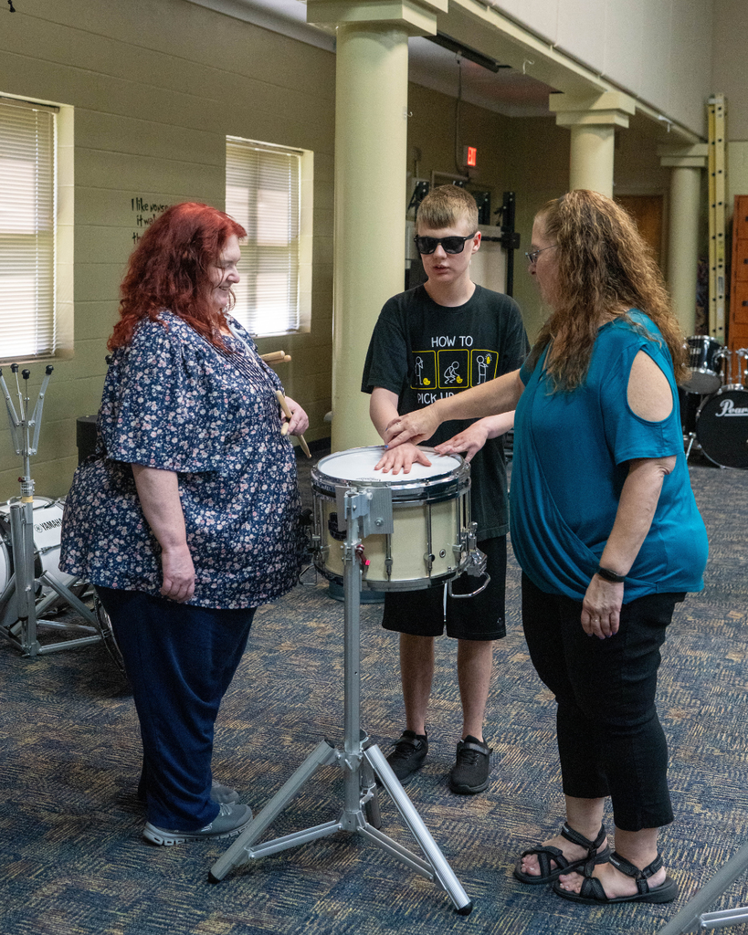 Two music teachers help a student out with the drums in the music building.