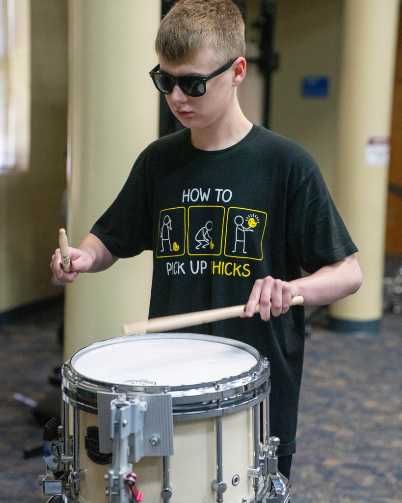 Student plays the drums in the music building.