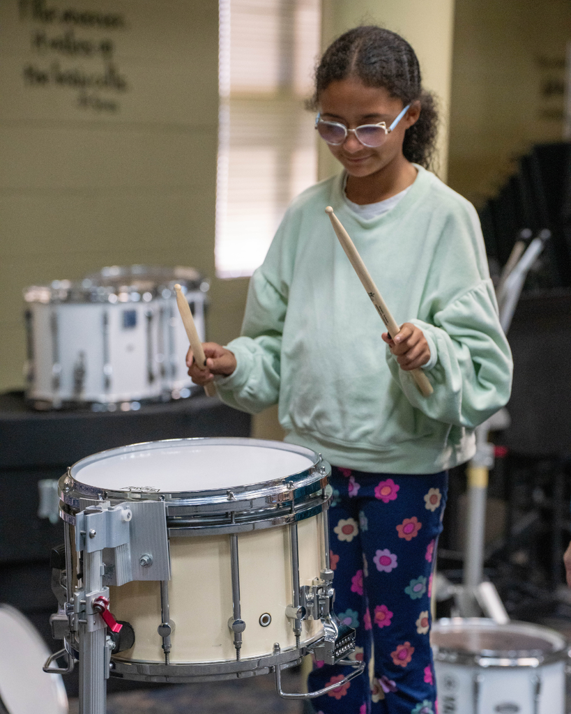 Student plays the drums in the music building.