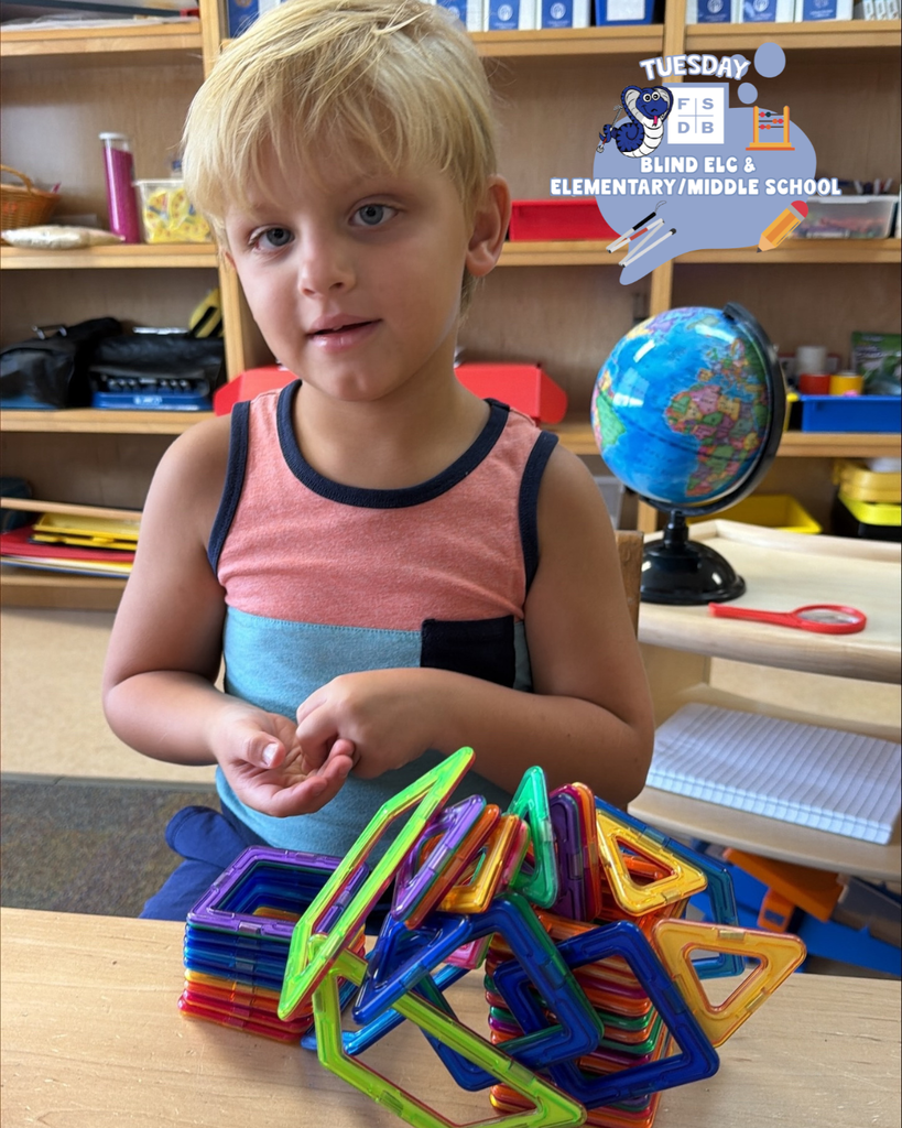A ELC blind student smiles for his photo with a toy he is playing with inside the classroom.
