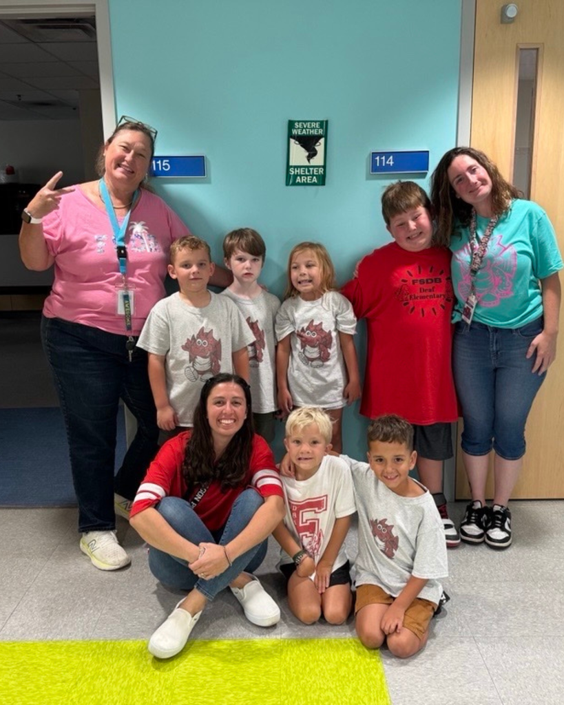 Group of students wear dragon wear smile for a photo in the hallway.