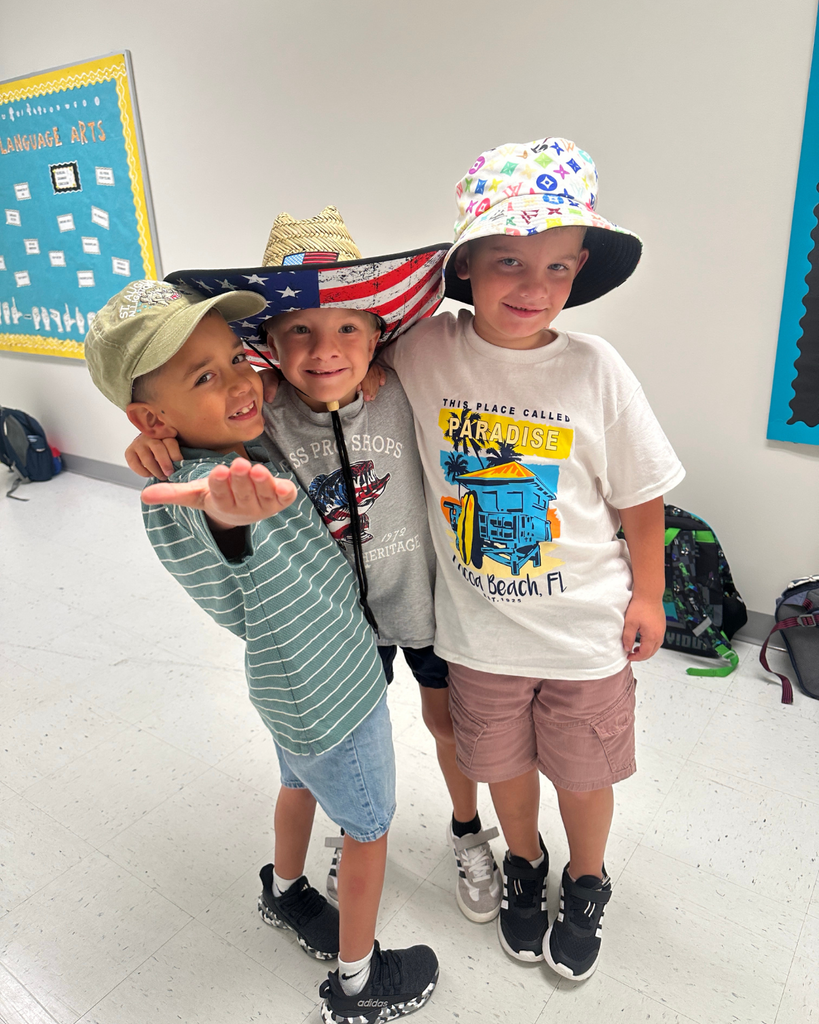 Three students wear hats smiling for a photo together.