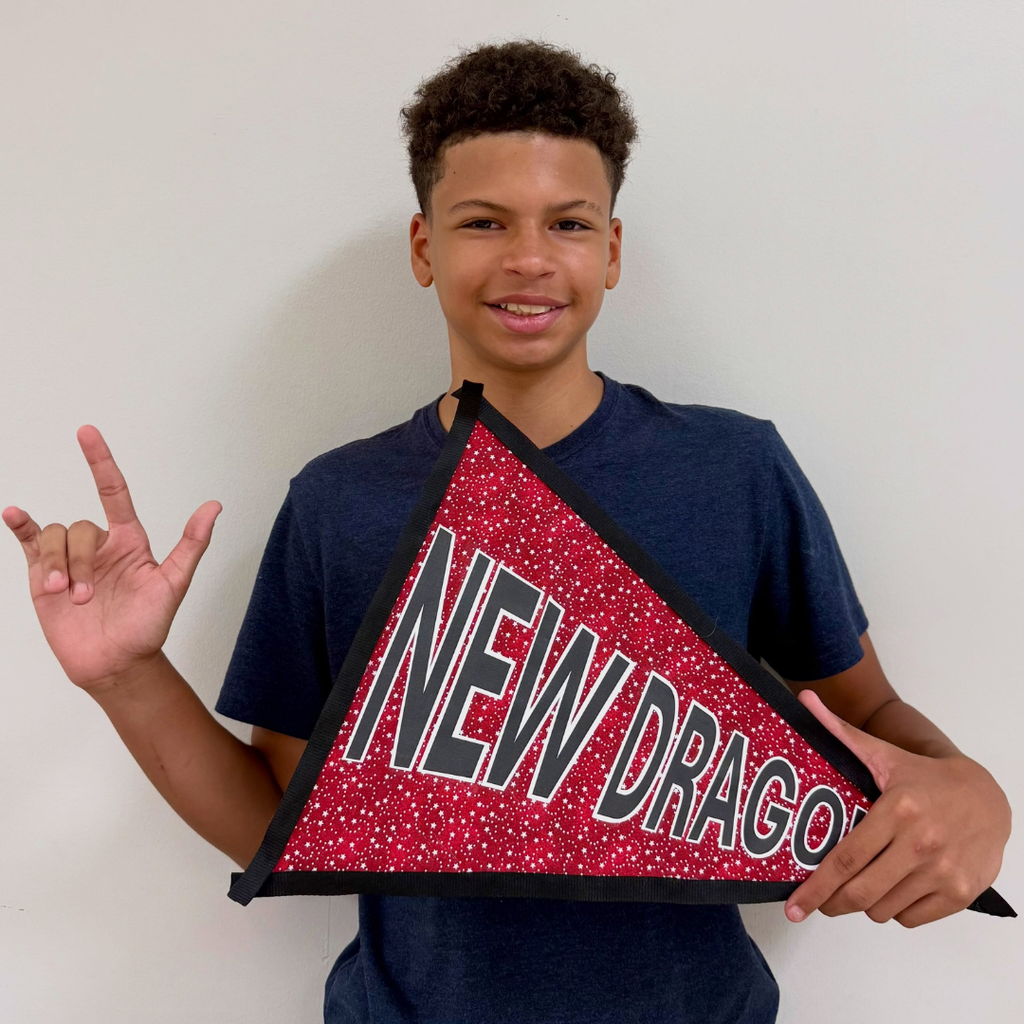 A student holds the "New Dragon" flag and signs "ILY" for the photo. 