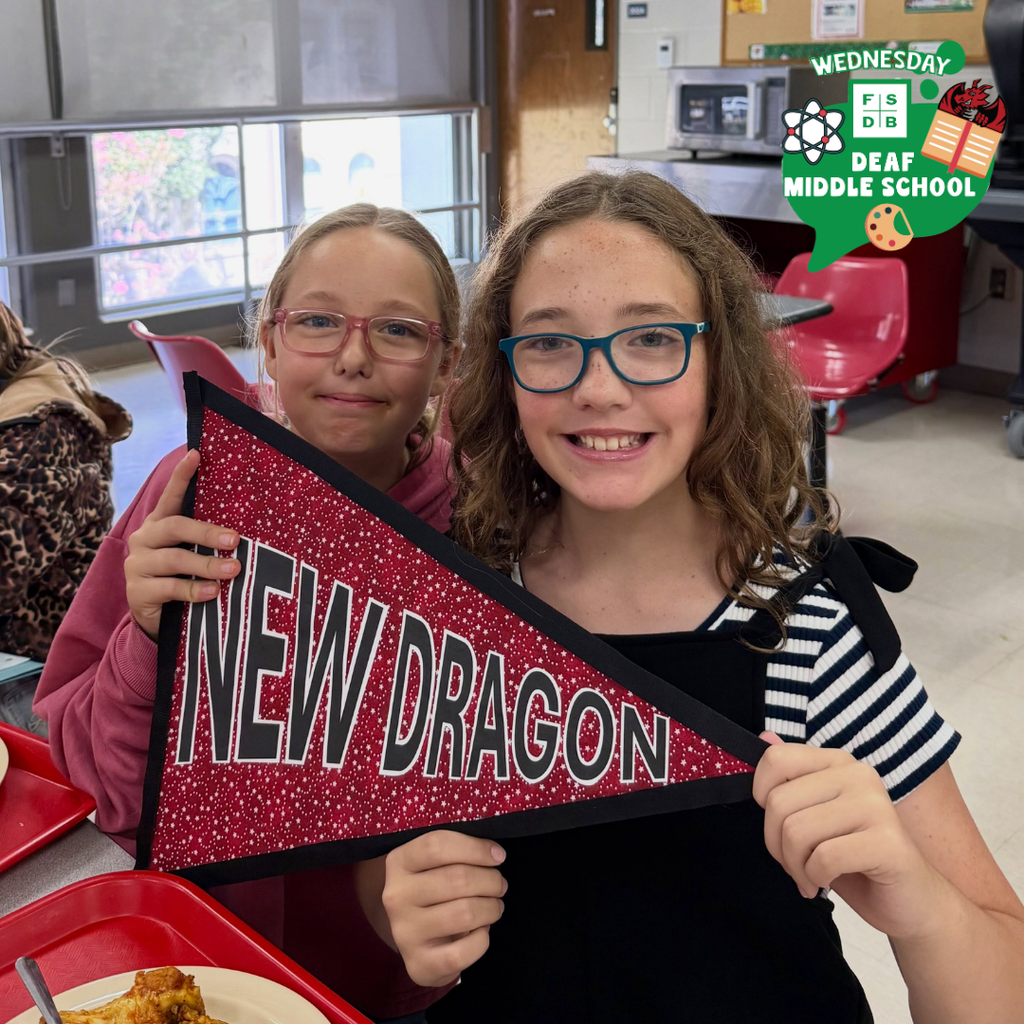 Two students hold a "New Dragon" flag smiles for their photo. 