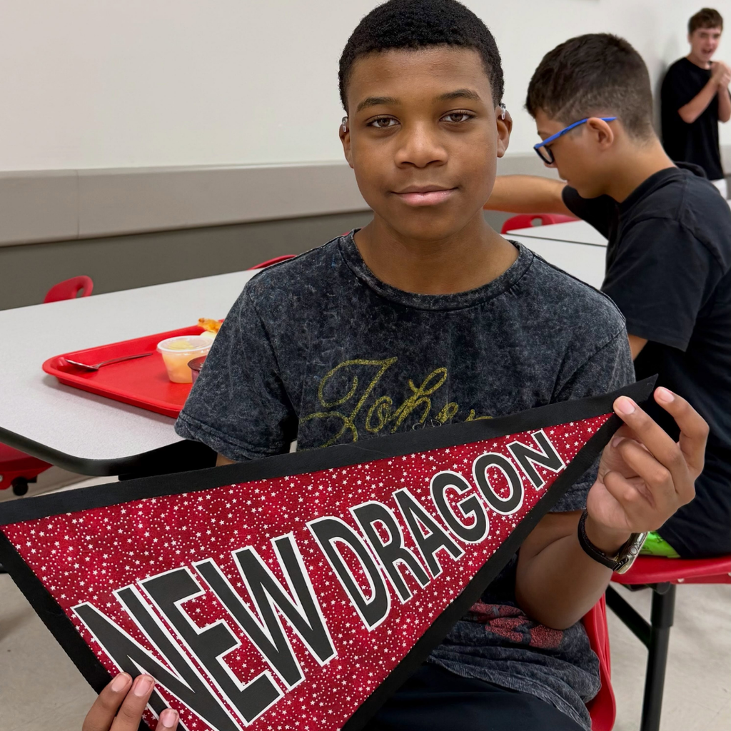 A student holds the "New Dragon" sign. 