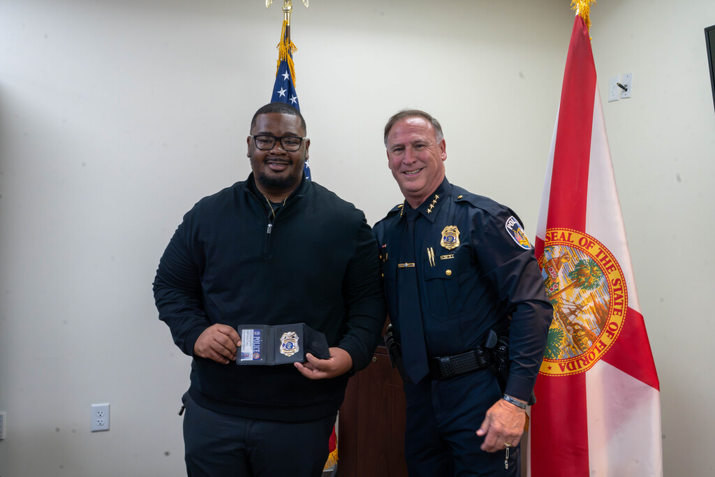 Chief and Ne'Darrius smiles for a photo together with the American flag and Florida flag behind them.