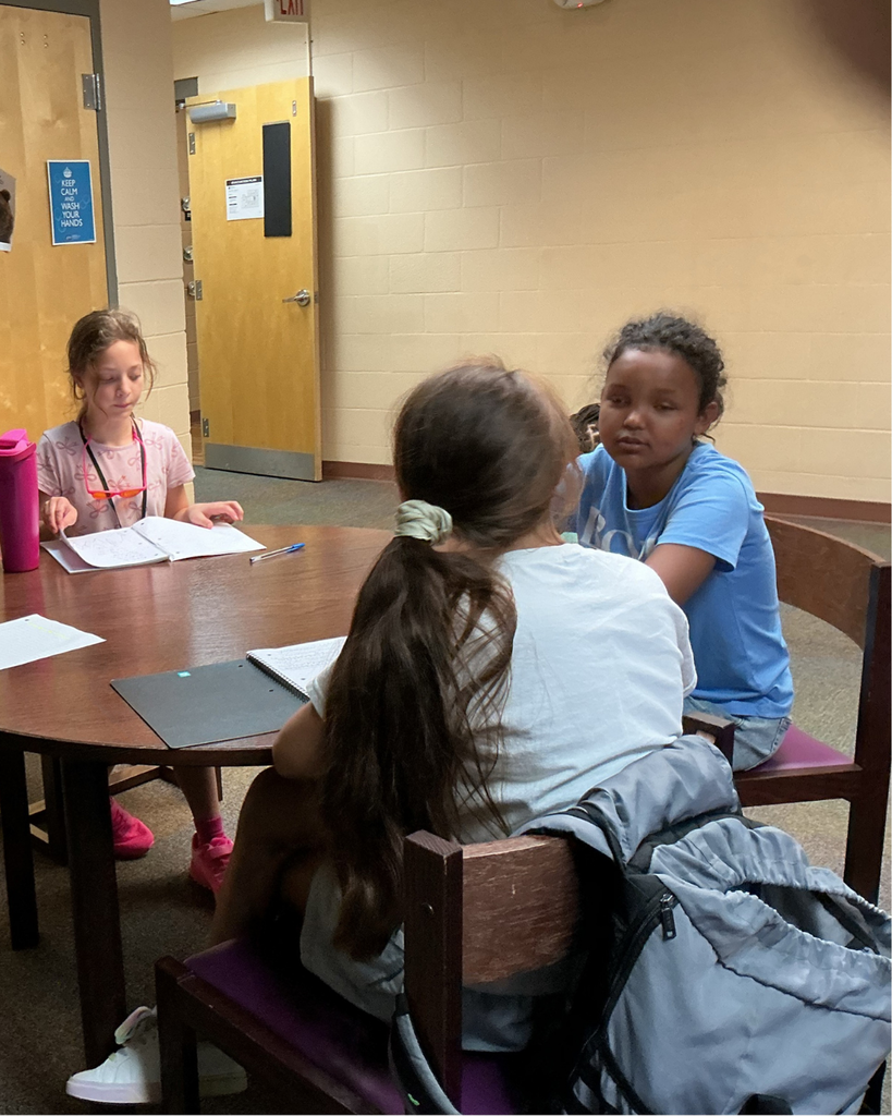 Three students work on homework together at a table. .