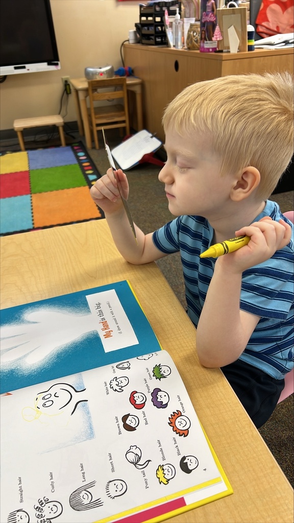 A ELC student is looking at himself in the mirror to fill out his "All about Me" book inside the classroom.