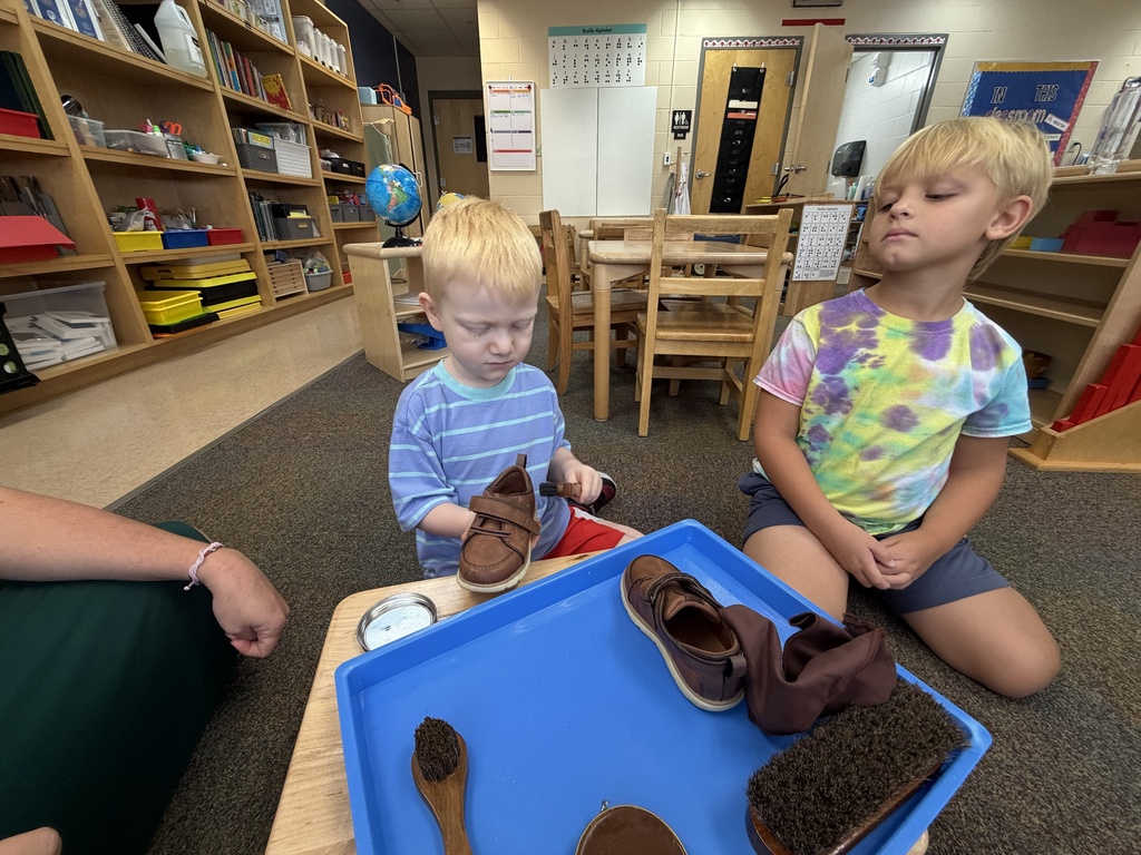 Two ELC students learn how to shine shoes together inside the classroom.