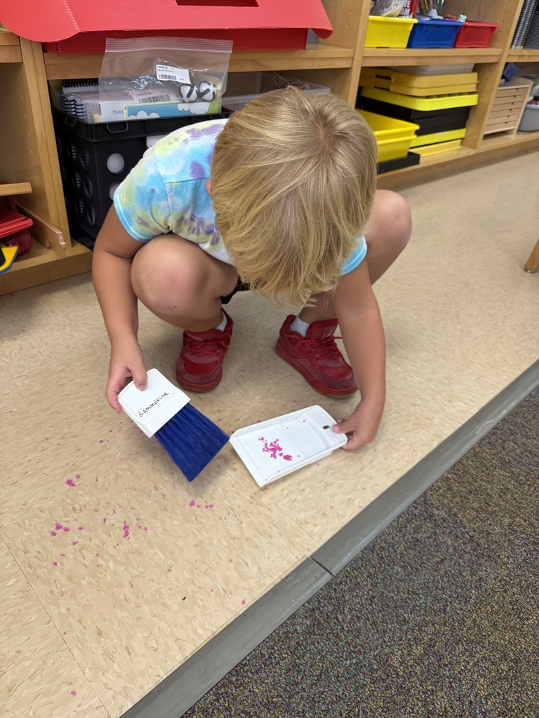A ELC student is learning how to clean up a mess on the floor.