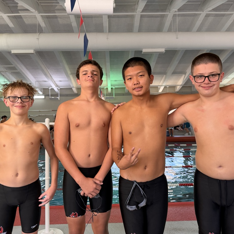 4 DMS swimmers posing in front of the pool 