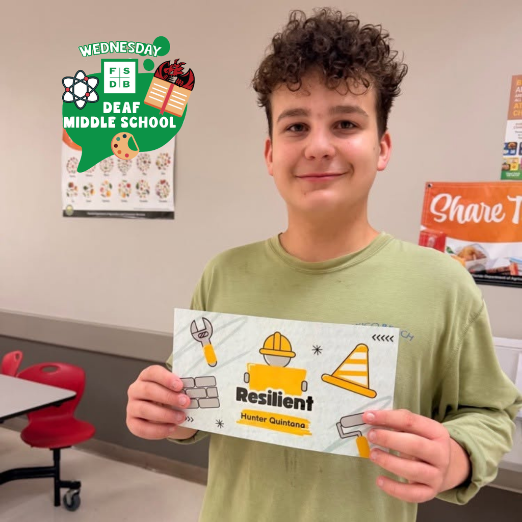 A student smiles with his "Resilient" card inside the cafeteria. 