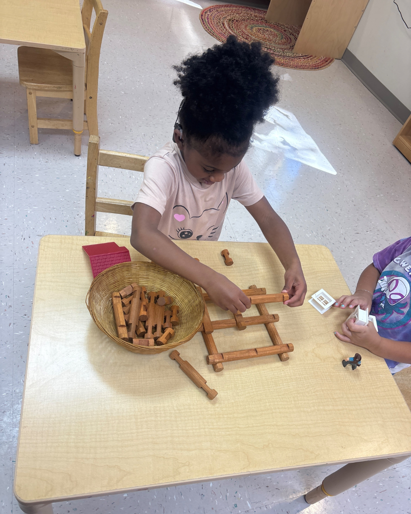 A student works on building a tower made out of logs. 