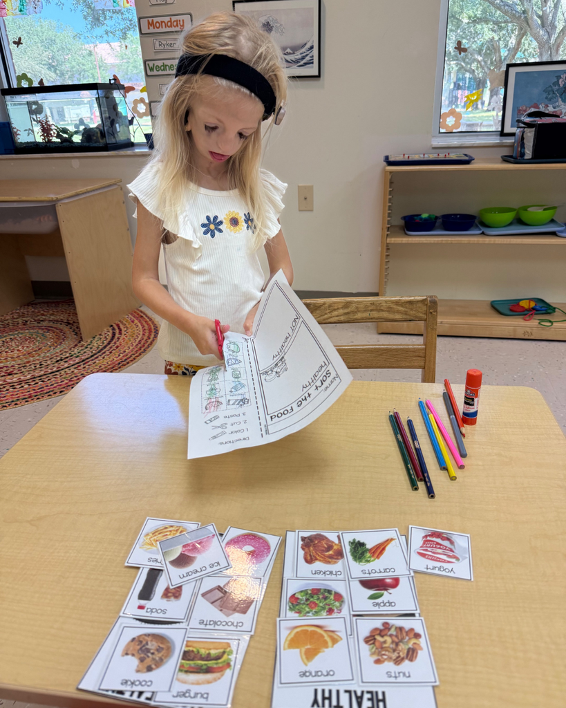 A ELC student cuts and sorts the food from Healthy and not Healthy. 