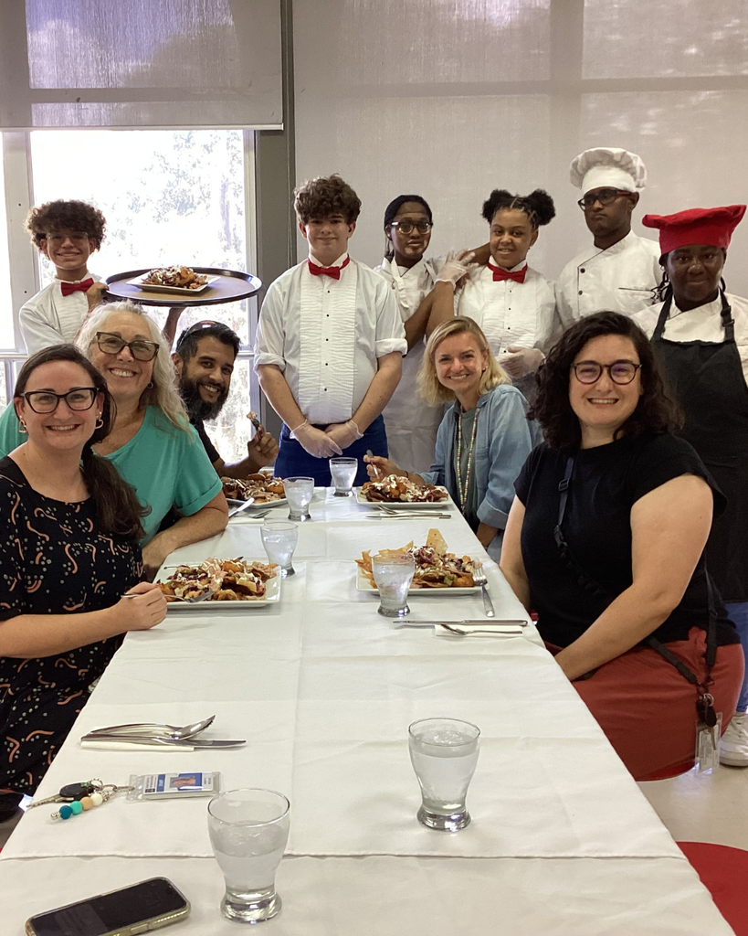Group of DHS staff and culinary students smile for their photo inside the cafeteria.