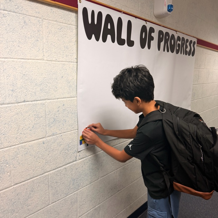 student adding his block to the wall of progress