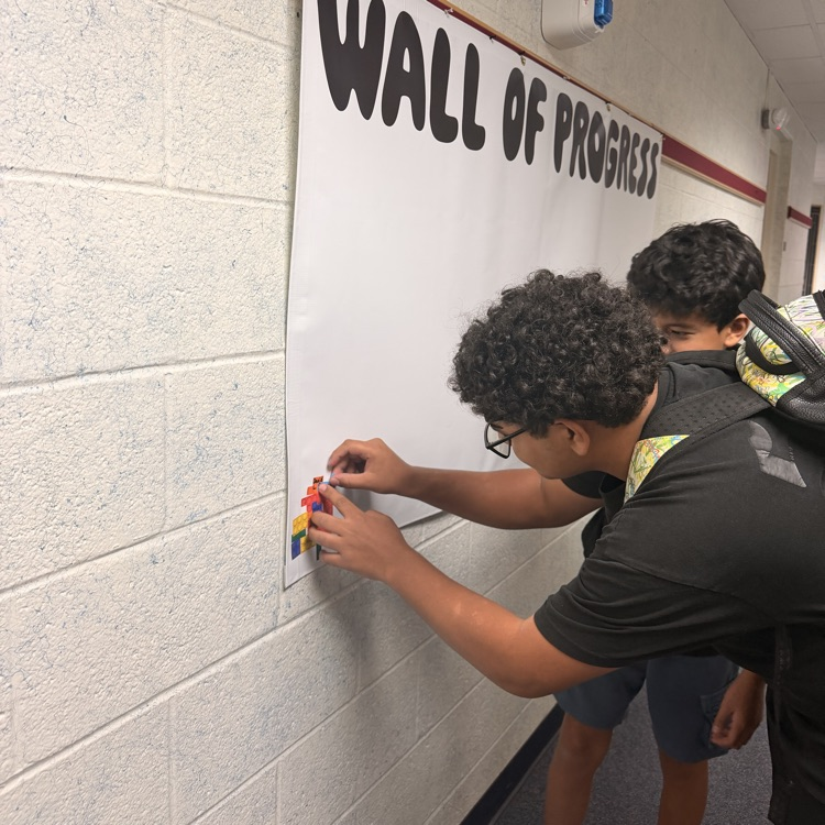 student adding his block to the wall of progress