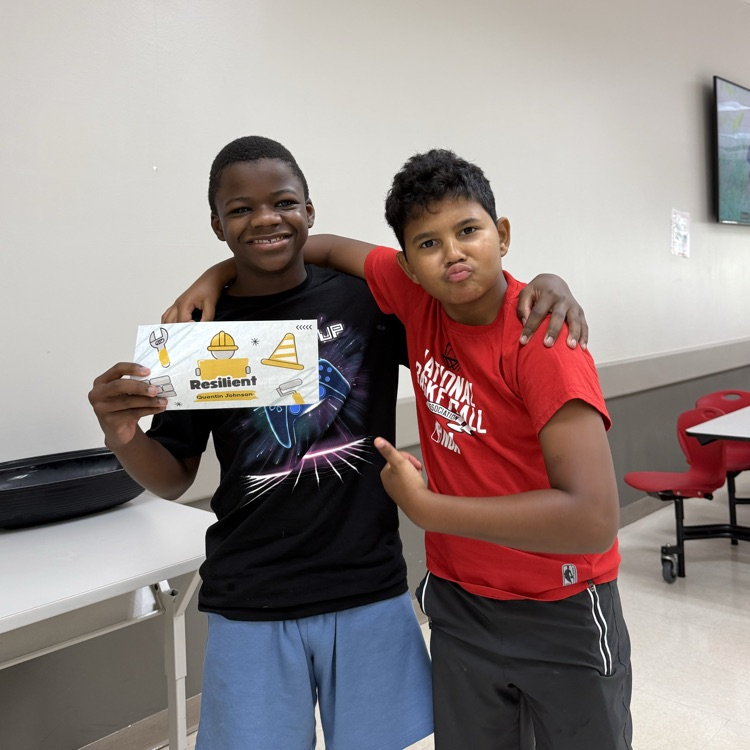 Two students stand close together holding Resiliency Award.