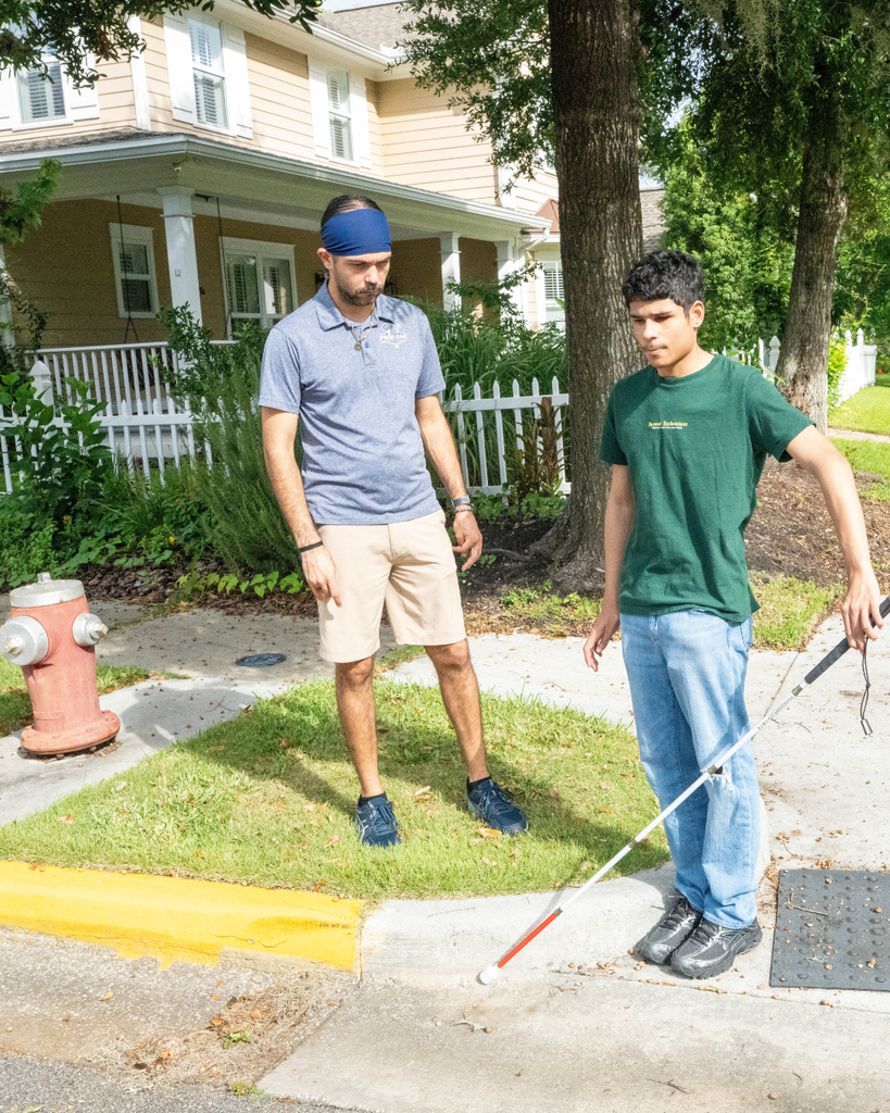 Carlos and Marco stand by the end of the sidewalk getting ready to cross the street.