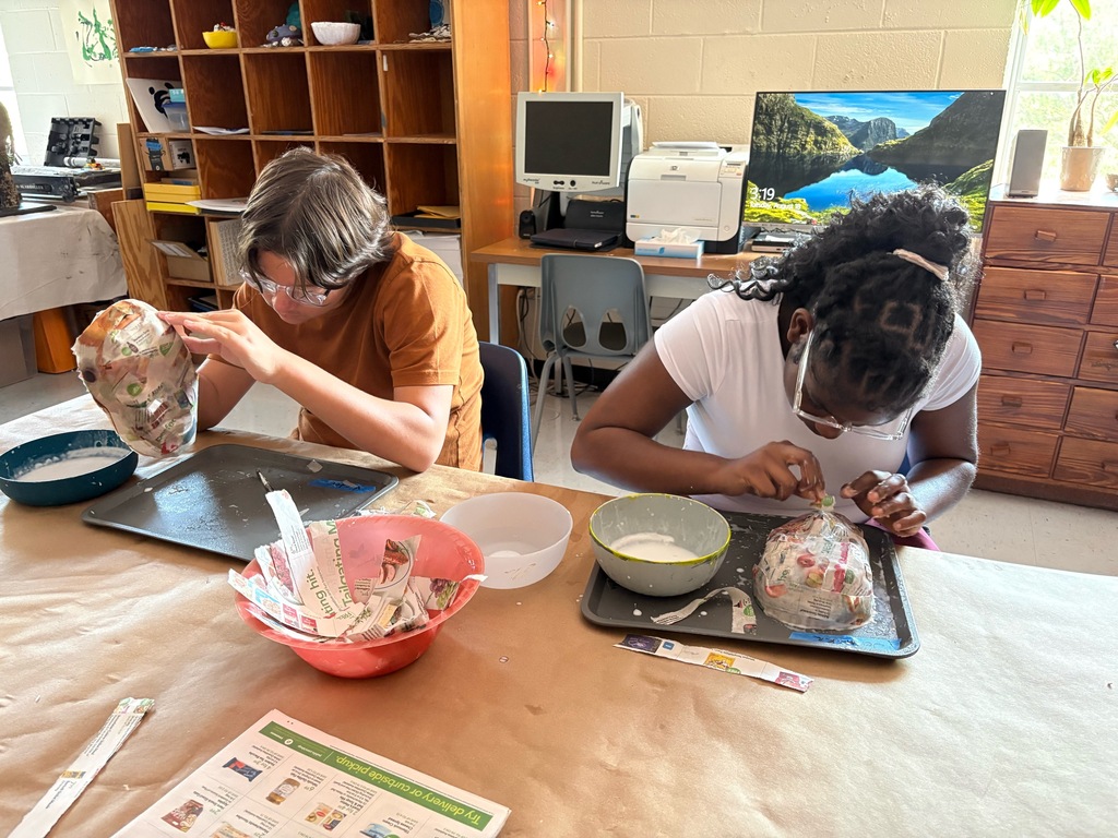Victor and Jermeka are adding the final layers of newspaper and paste to their masks.