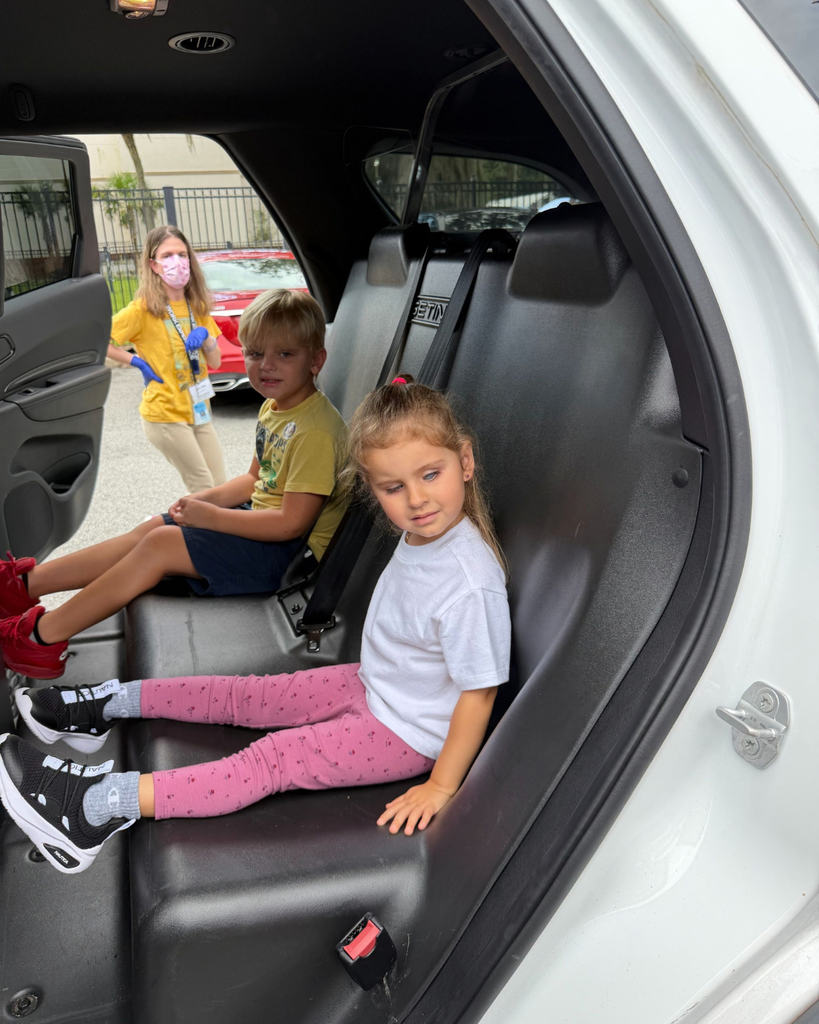 Two ELC students sat in the back of a police car.