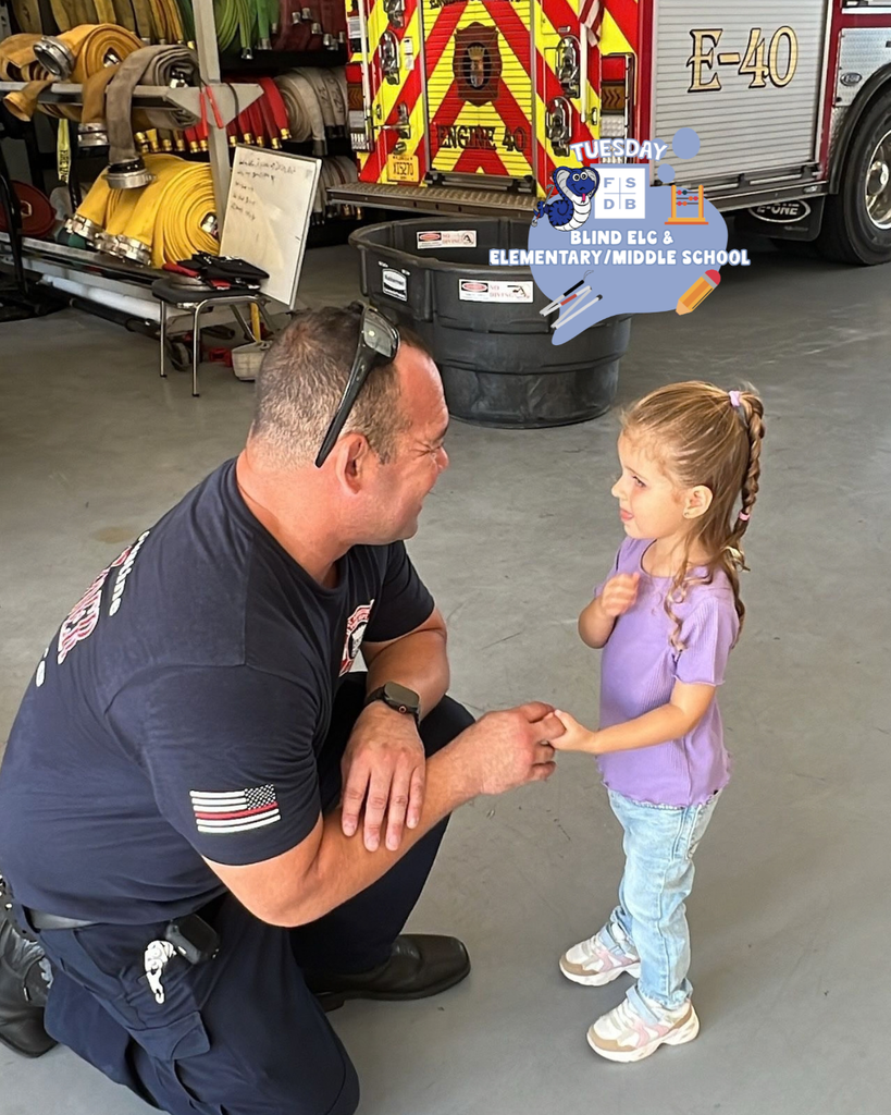 A ELC student hold hands with a firefighter inside the house.