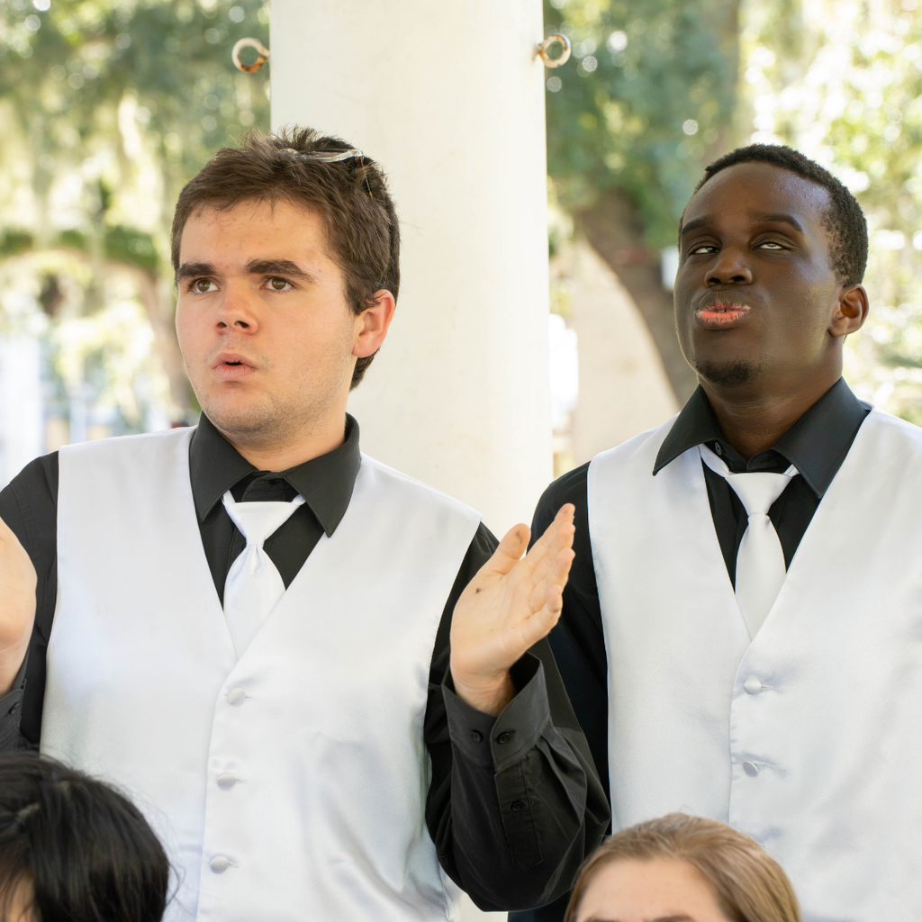 Two students wear white and black suit sing outside downtown St. Augustine.