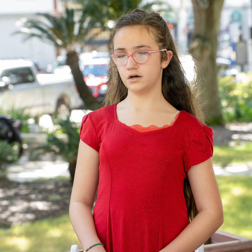 A student wear a red sparkly dress sing outside downtown St Augustine.