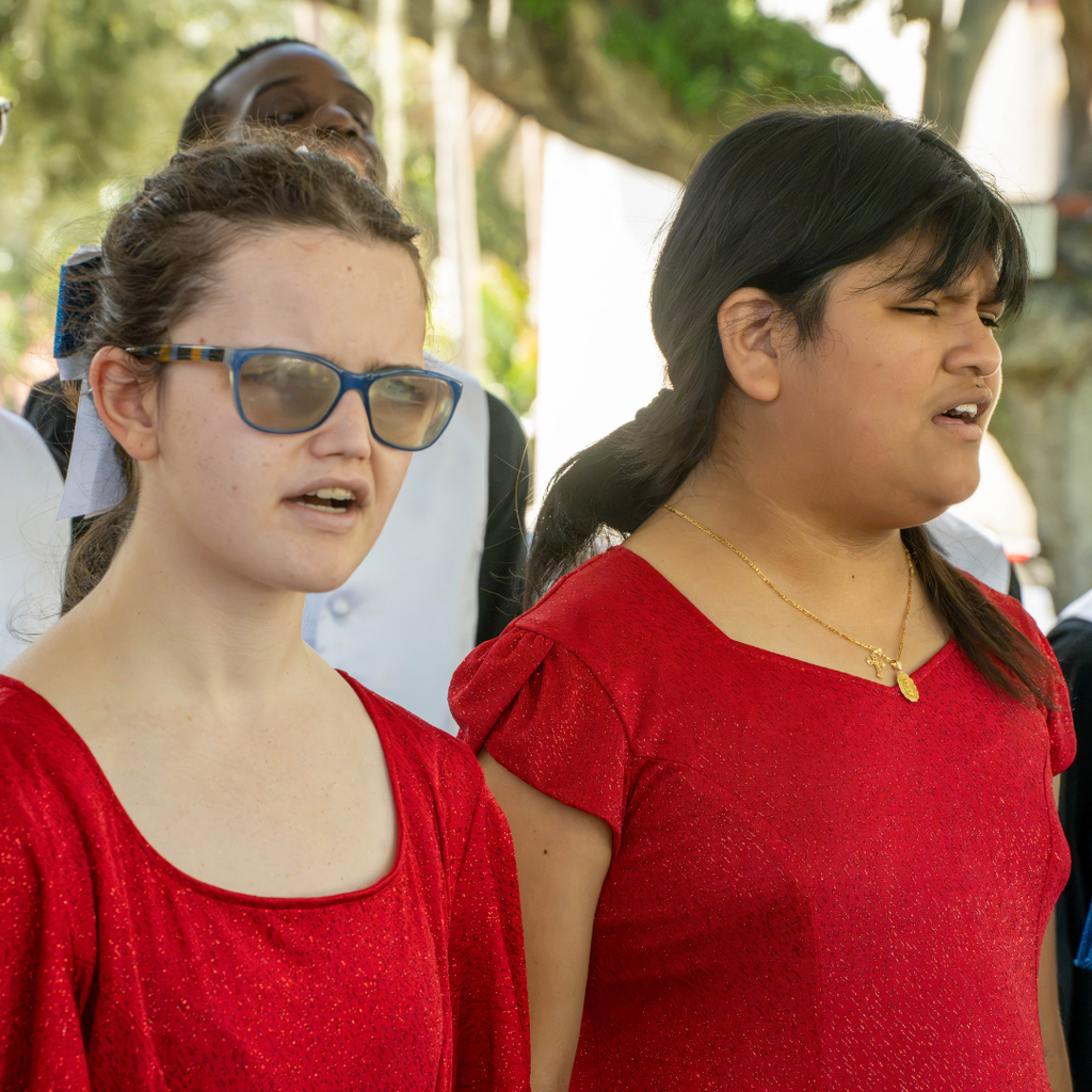 Two students wear sparkly red dresses sing outside downtown St. Augustine.