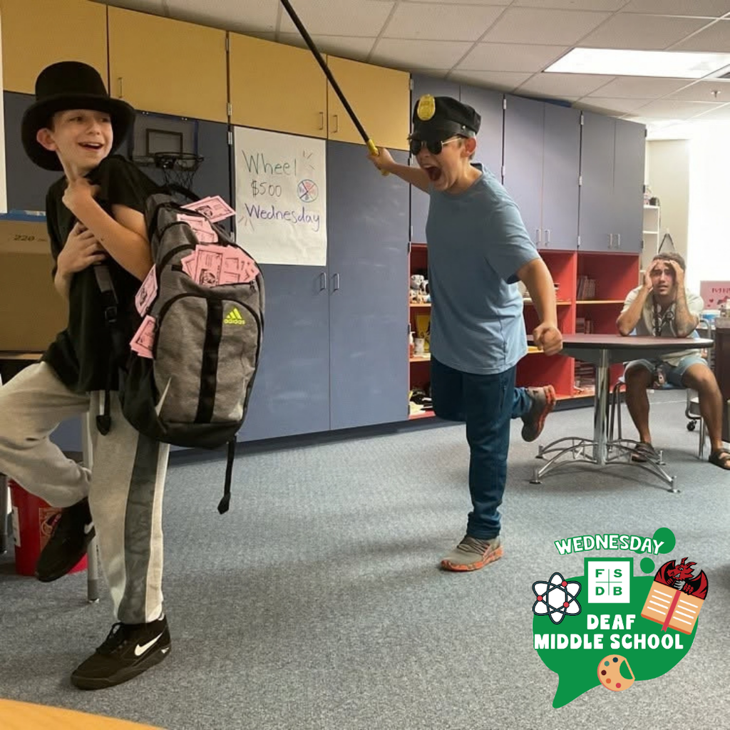 A student on the left is holding a backpack with fake money while the student on the right wears a cop hat and tries to catch the student with backpack.