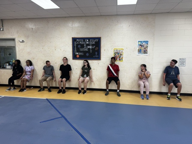 Students doing wall sits in Copeland lobby.