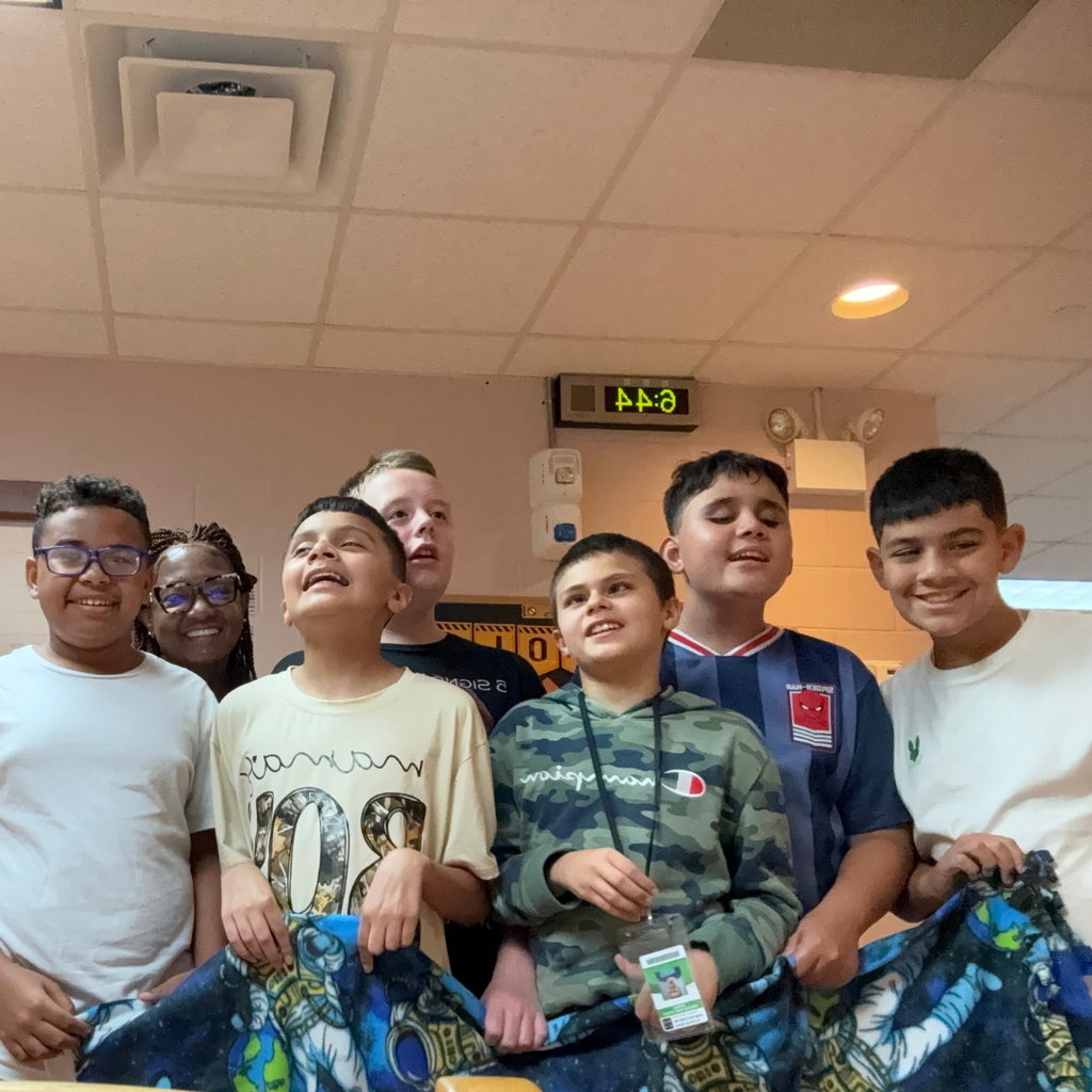 Group of students smile with the blanket and Ms. Laronda for a photo inside Cary White. 