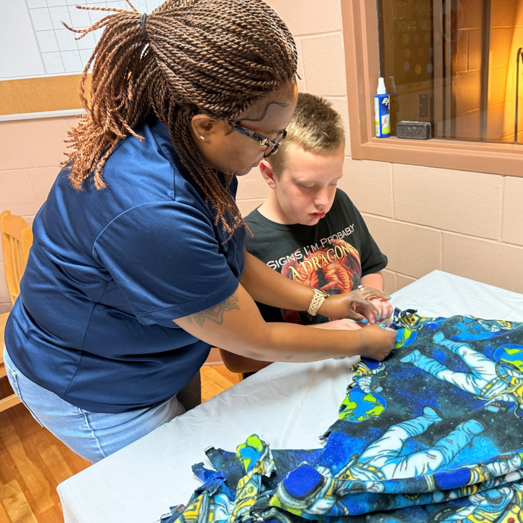 Ms. Laronda helps a student sewing a blanket inside Cary White. 