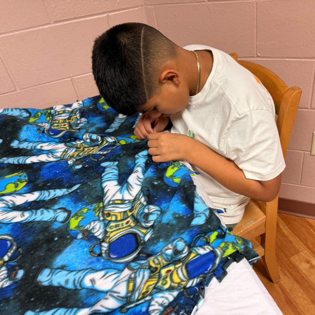 A student sews the blanket by himself inside Cary White. 