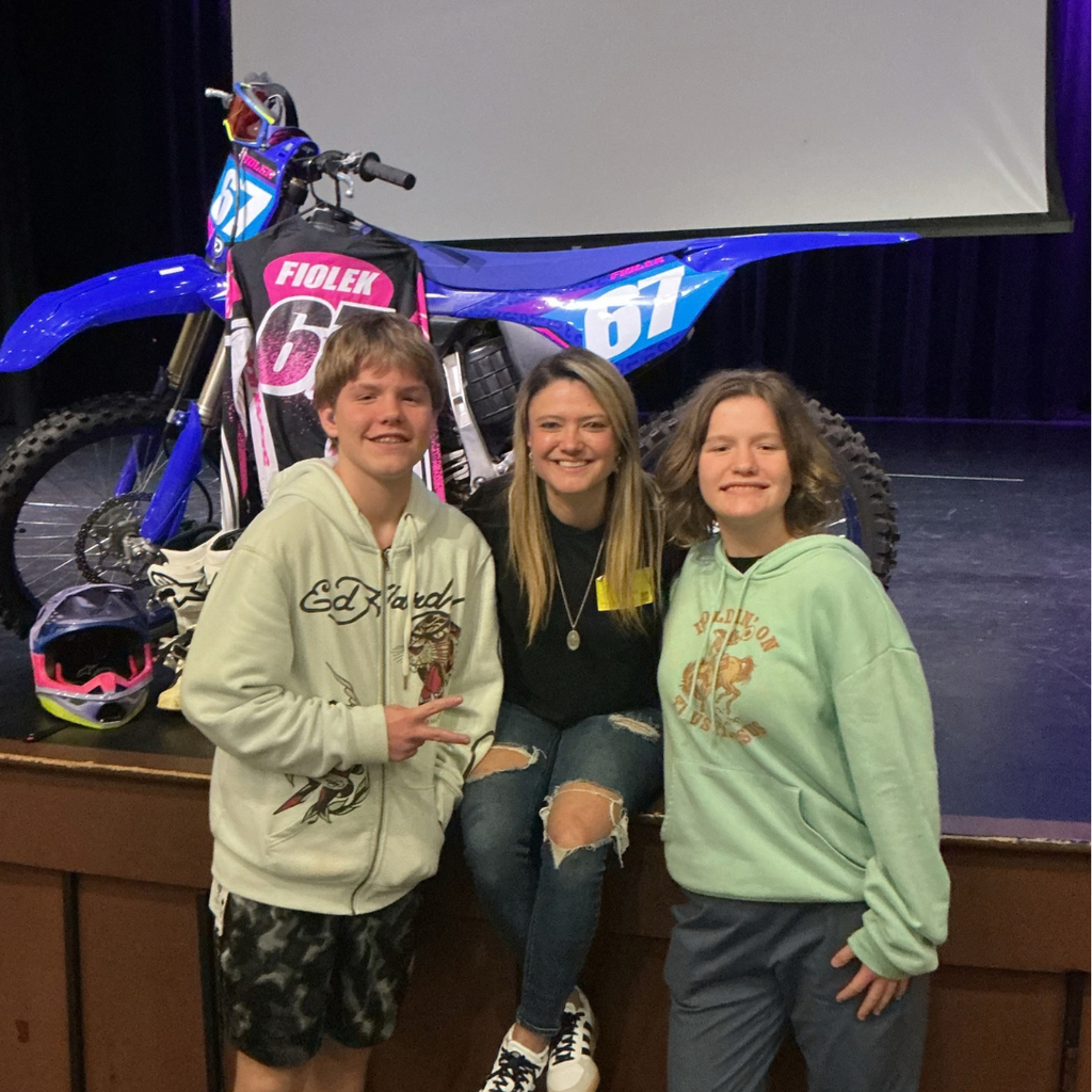 Ashley smiles with two students on stage in Kirk.