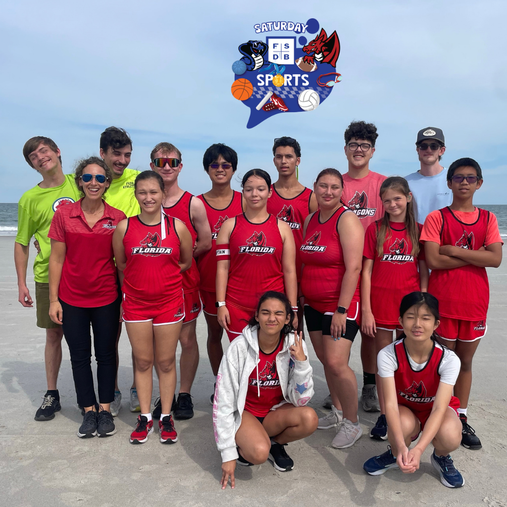 Cross Country team smile together for a photo outside at the beach.