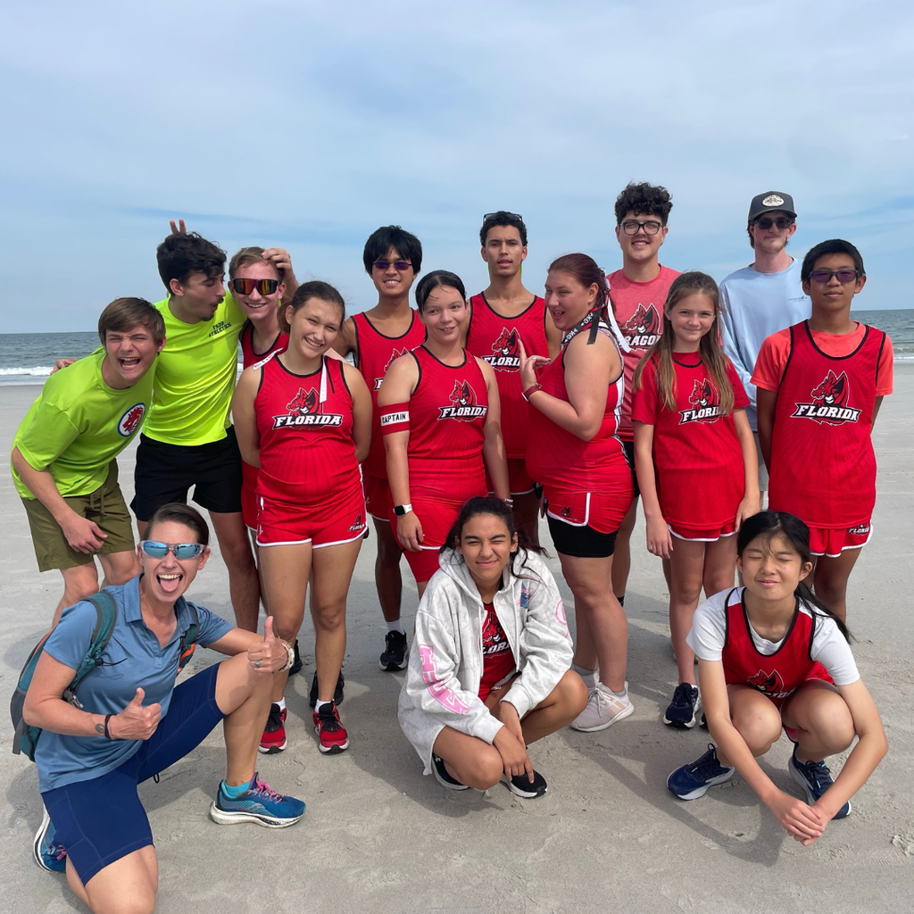 Cross Country team smile together for a photo outside at the beach.