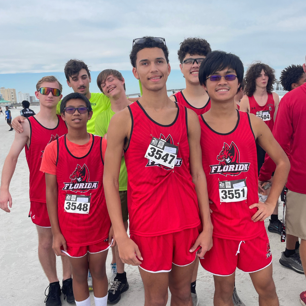 Boys Cross Country team smile together for a photo outside at the beach.