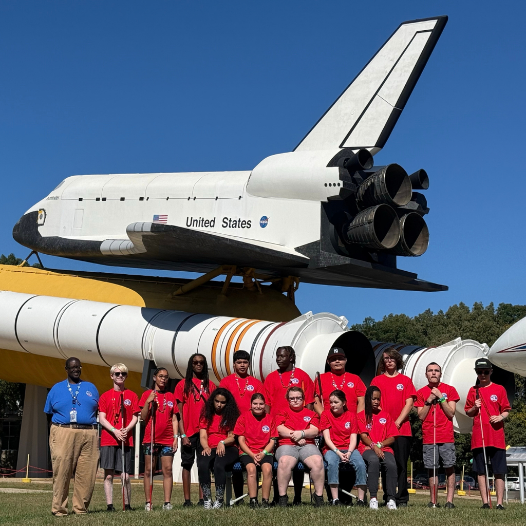 Group photo of the students who are attending the space camp by the rocket.