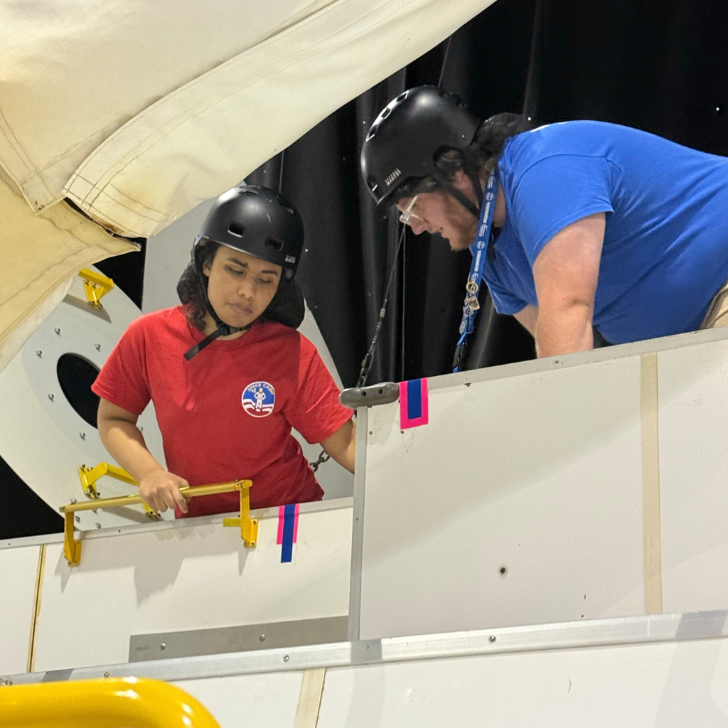 A student listens to instructor as she gets out of the rocket.