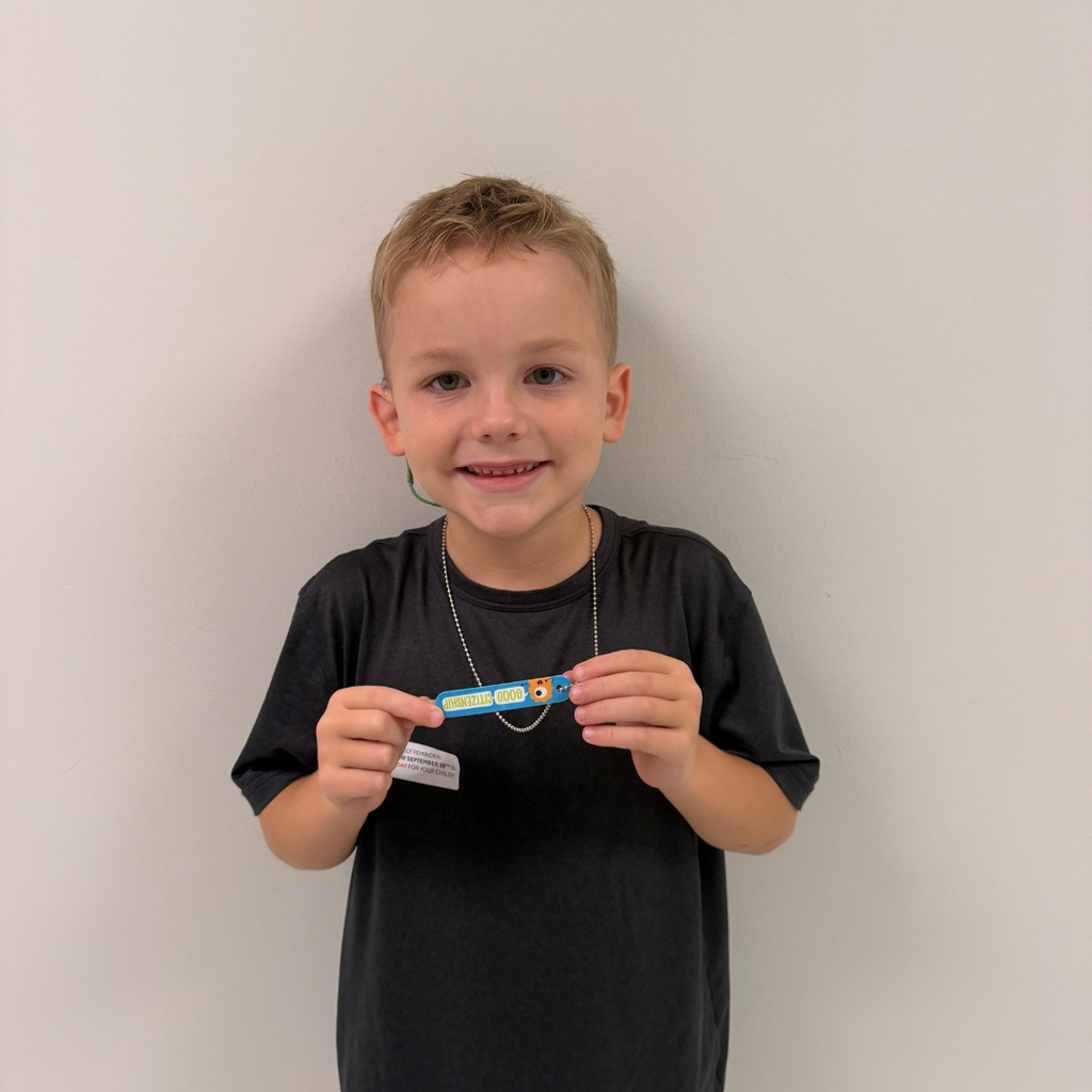 A student holds his citizenship award and smiles for a photo.