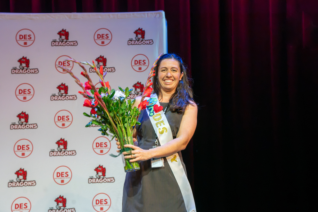 Brooke smiles and holds flowers on stage in Kirk. 