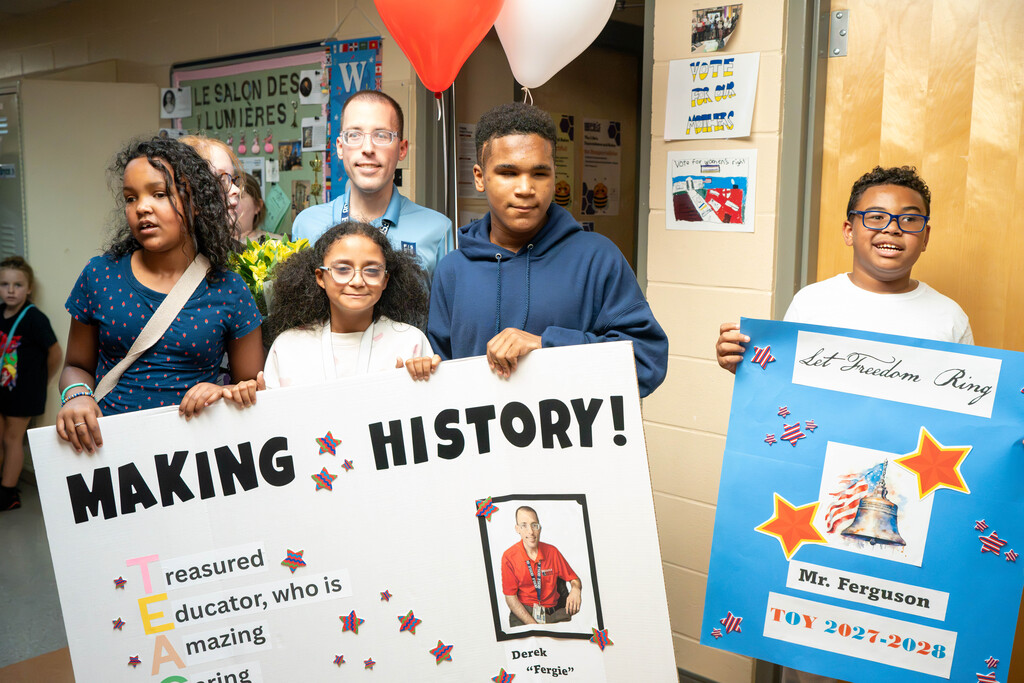 students holding a poster that reads "making history," that contains praise words and a photo of Mr. Ferguson.