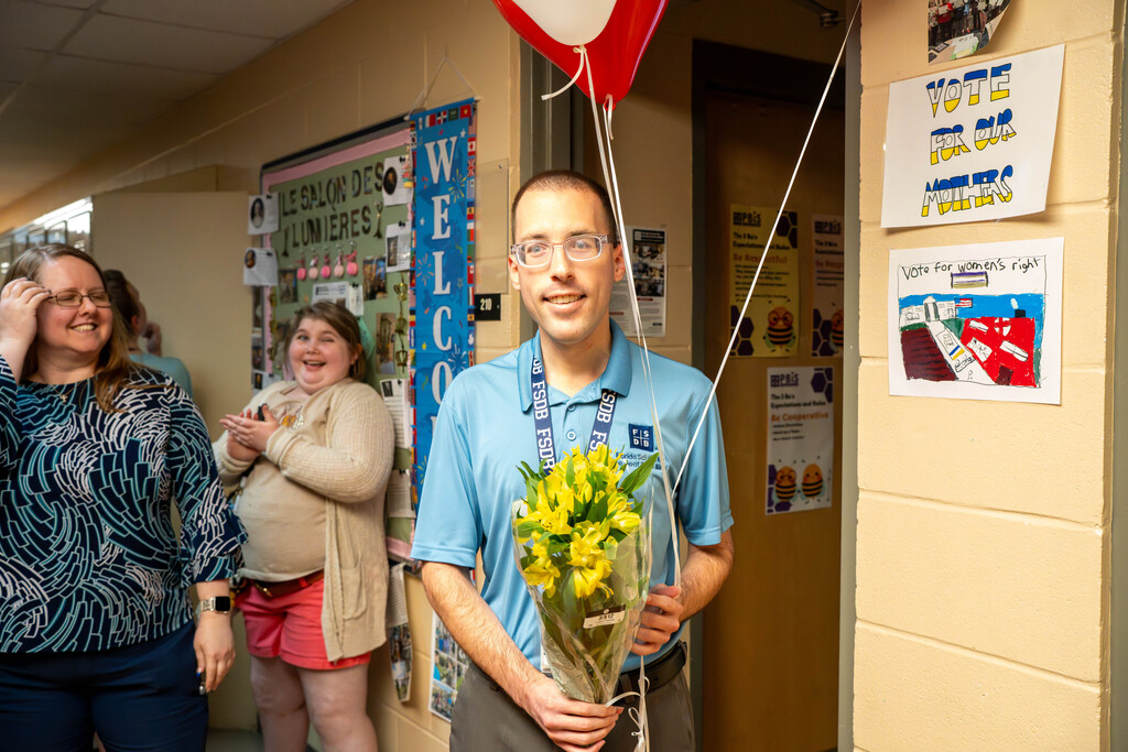 Mr. Ferguson smiling and holding a ballon and flowers.