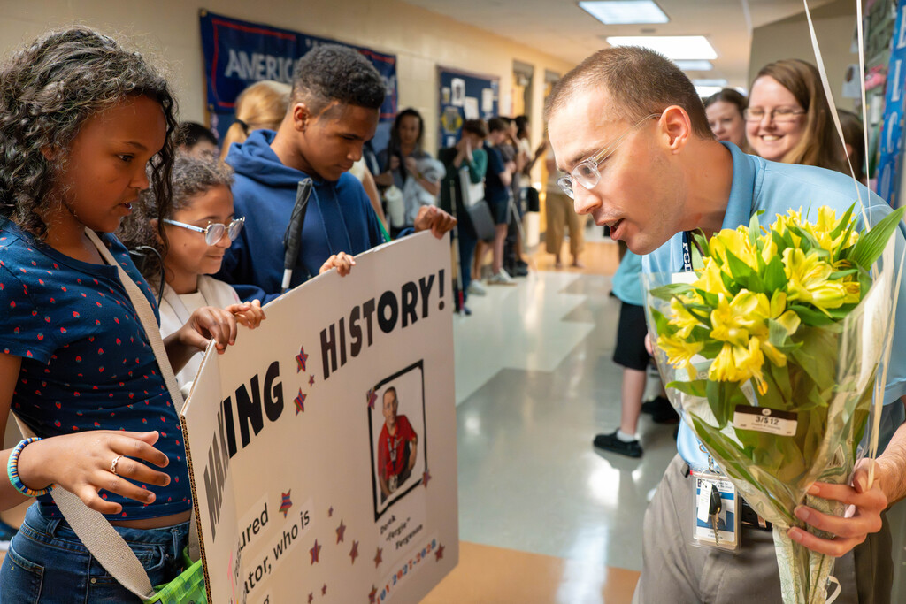 Mr. Ferguson holds flowers and read the sign his students made for him.