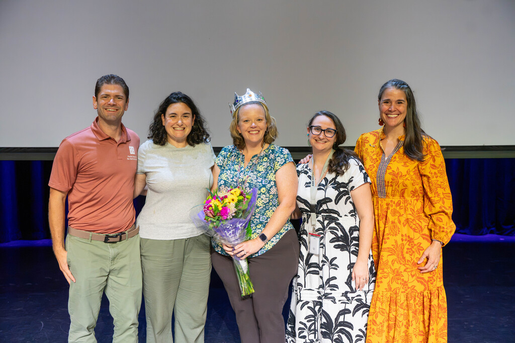 Brianna smiles with the administration team on stage in Kirk.