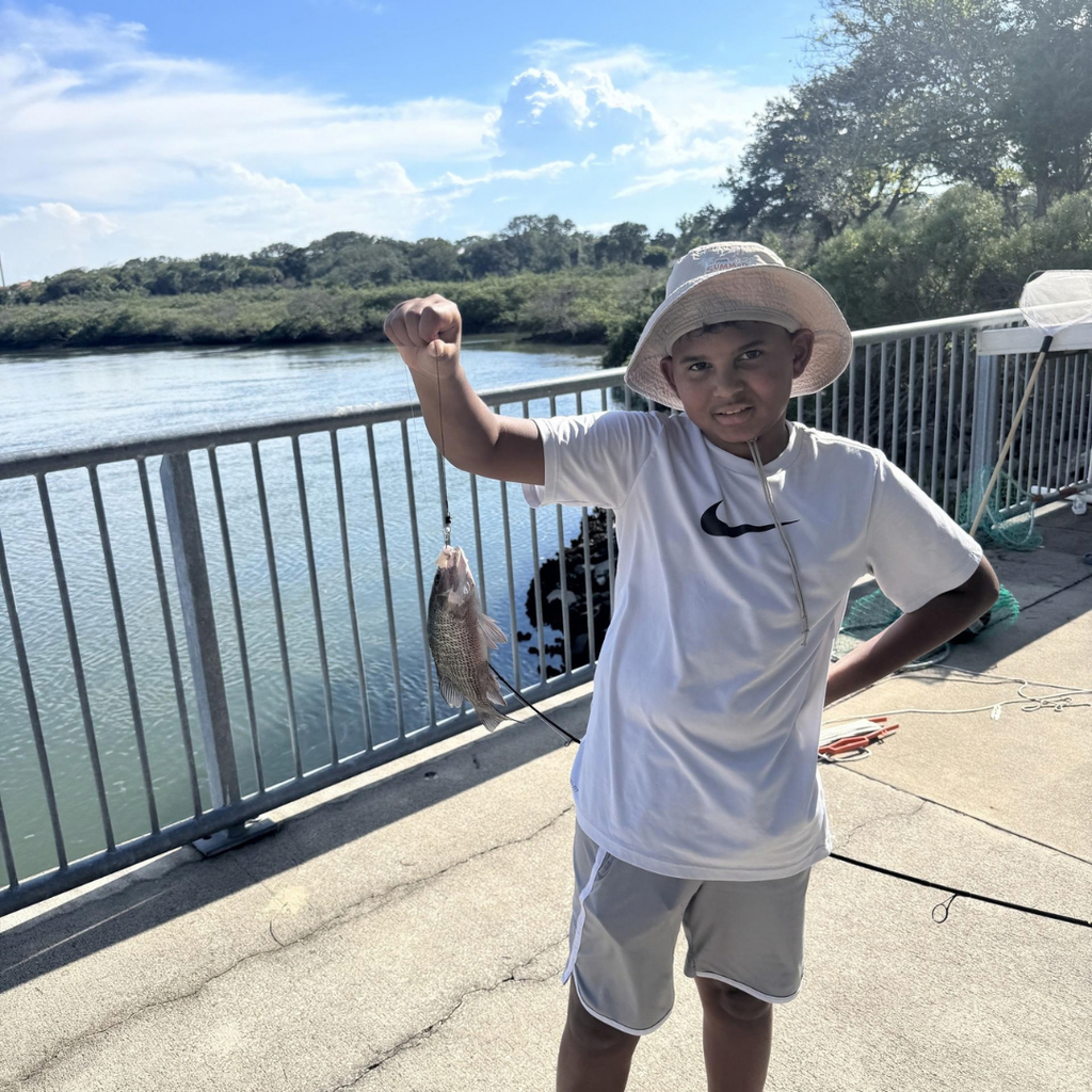 Student holds rod with fish on the end. 