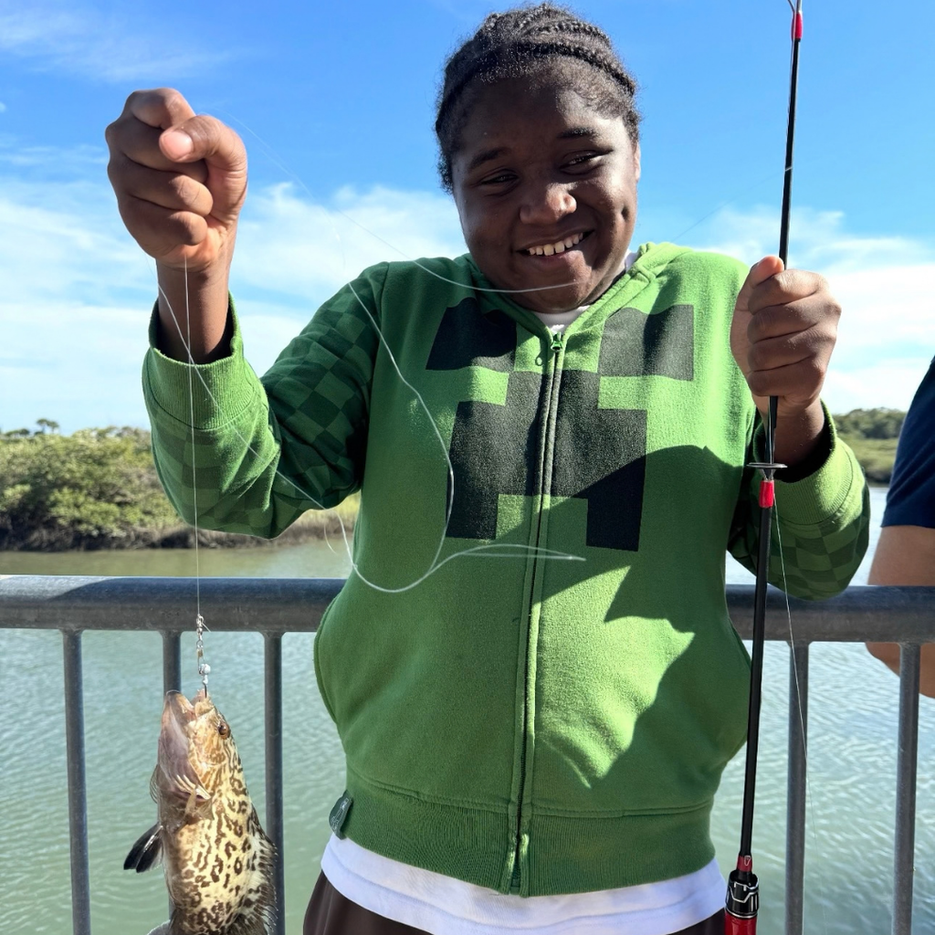 Student holds rod with fish on the end. 