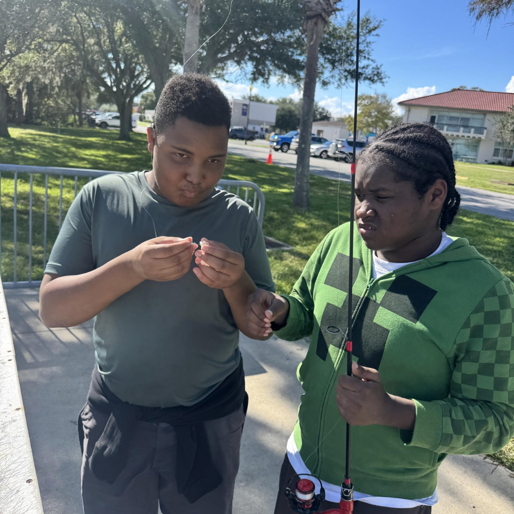 Two students adding bait to their fishing rod.