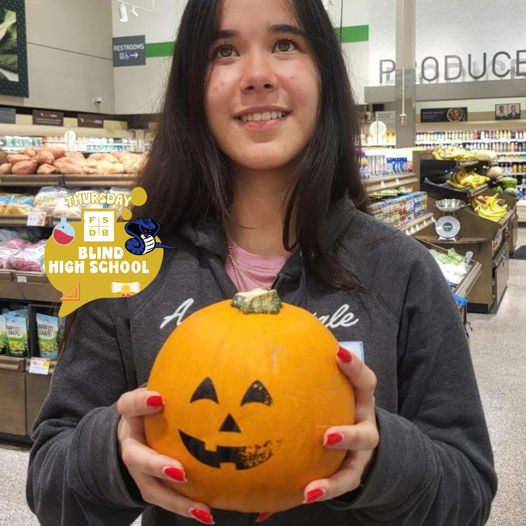 A student holds a painted pumpkin inside Publix.